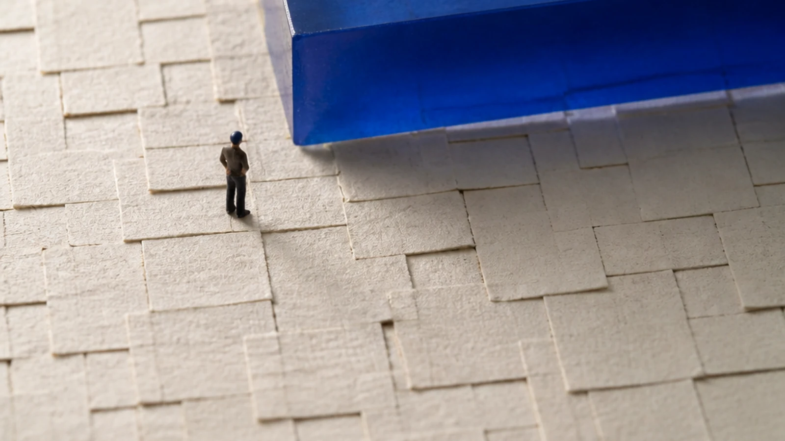 A translucent blue block rises from a small field of printed-paper squares.