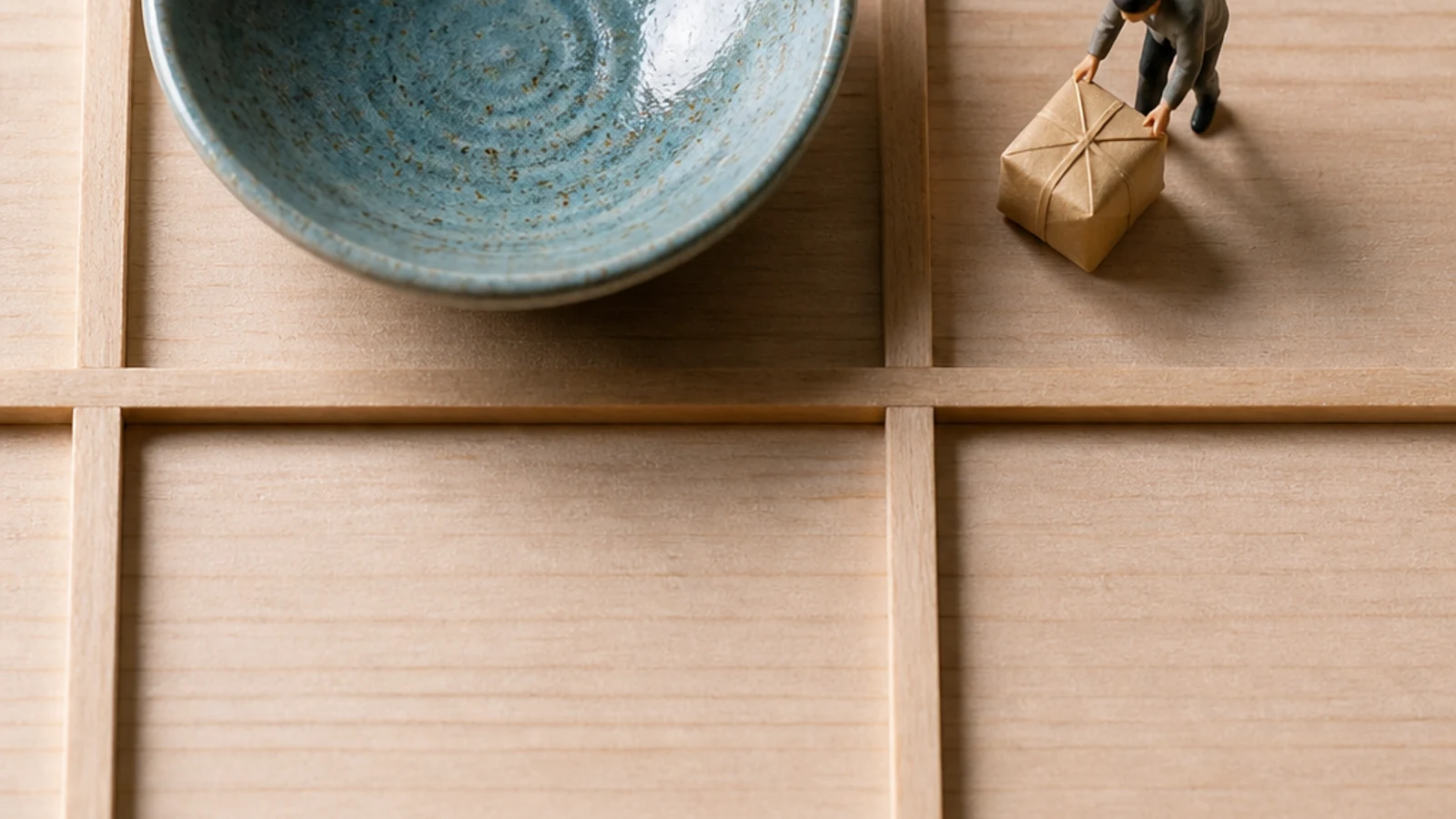 One blue-glazed bowl sits in a wide pale wooden grid.