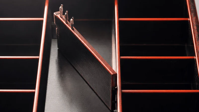 A lacquer bento box seen from above with one divider shifted out of place beneath three miniature figures.